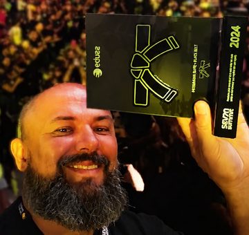 Evânio Garcia no palco do Seven Summit 2024, segurando a placa da faixa preta da Eduzz